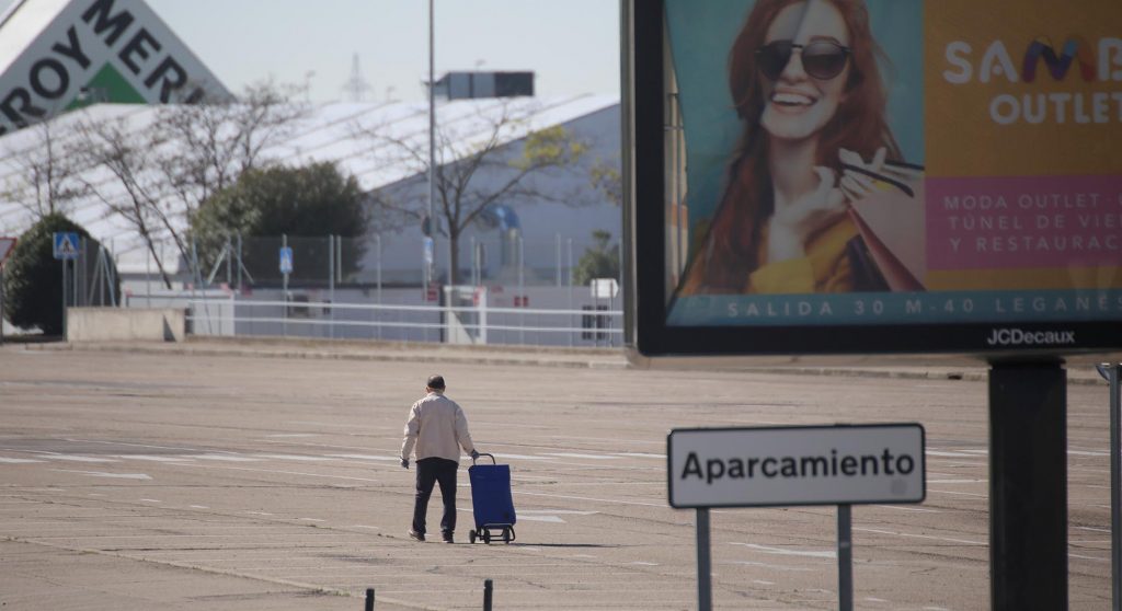 Una persona arrastra un carrito en el aparcamiento de un centro comercial en Madrid